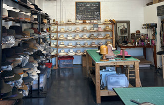 Hat shop interior with shelves of hats and a worktable.